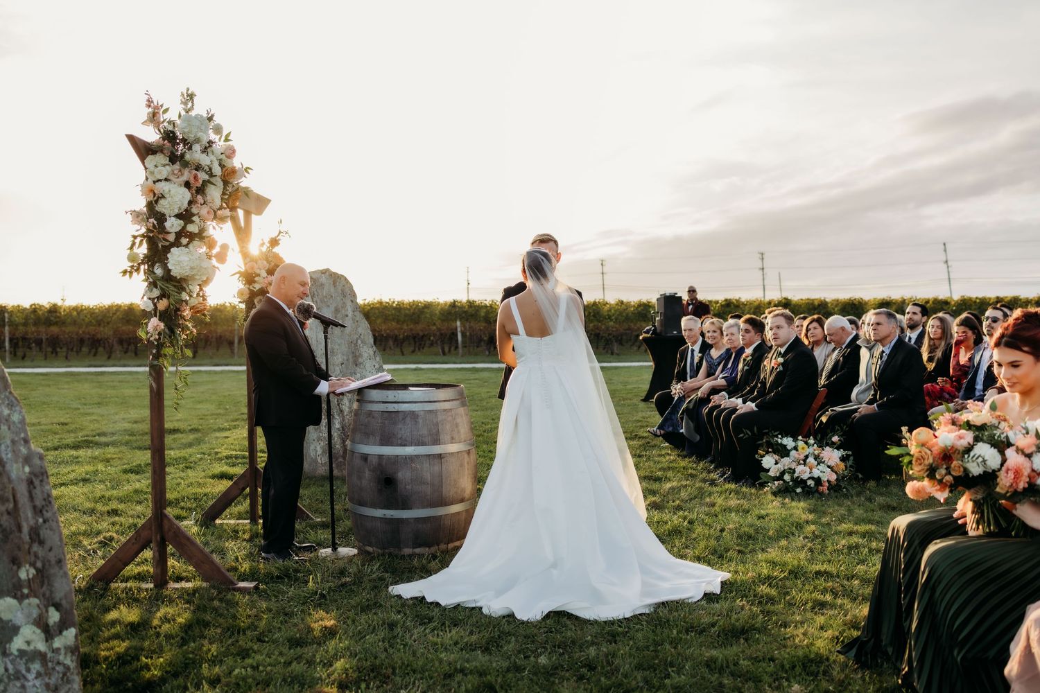 A series of romantic sunset wedding photos showing couples and guests celebrating outdoors near rustic wine barrels.
