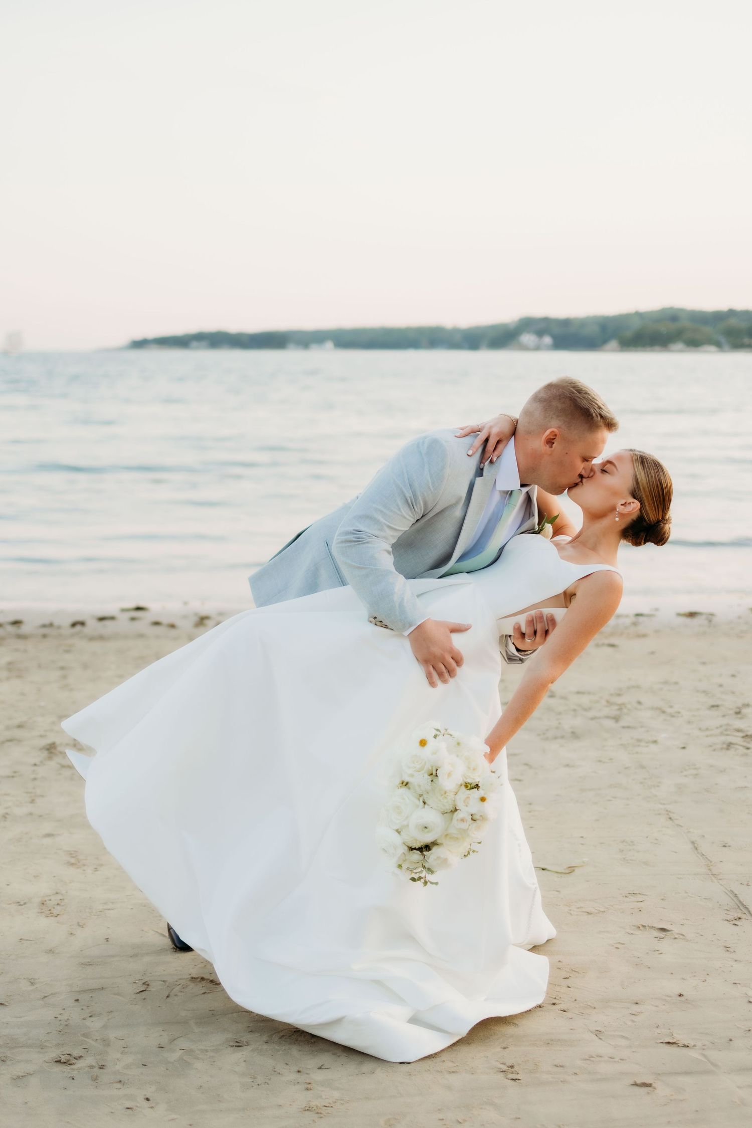 Romantic beach wedding photos showing couple dipping and dancing on sandy shoreline.