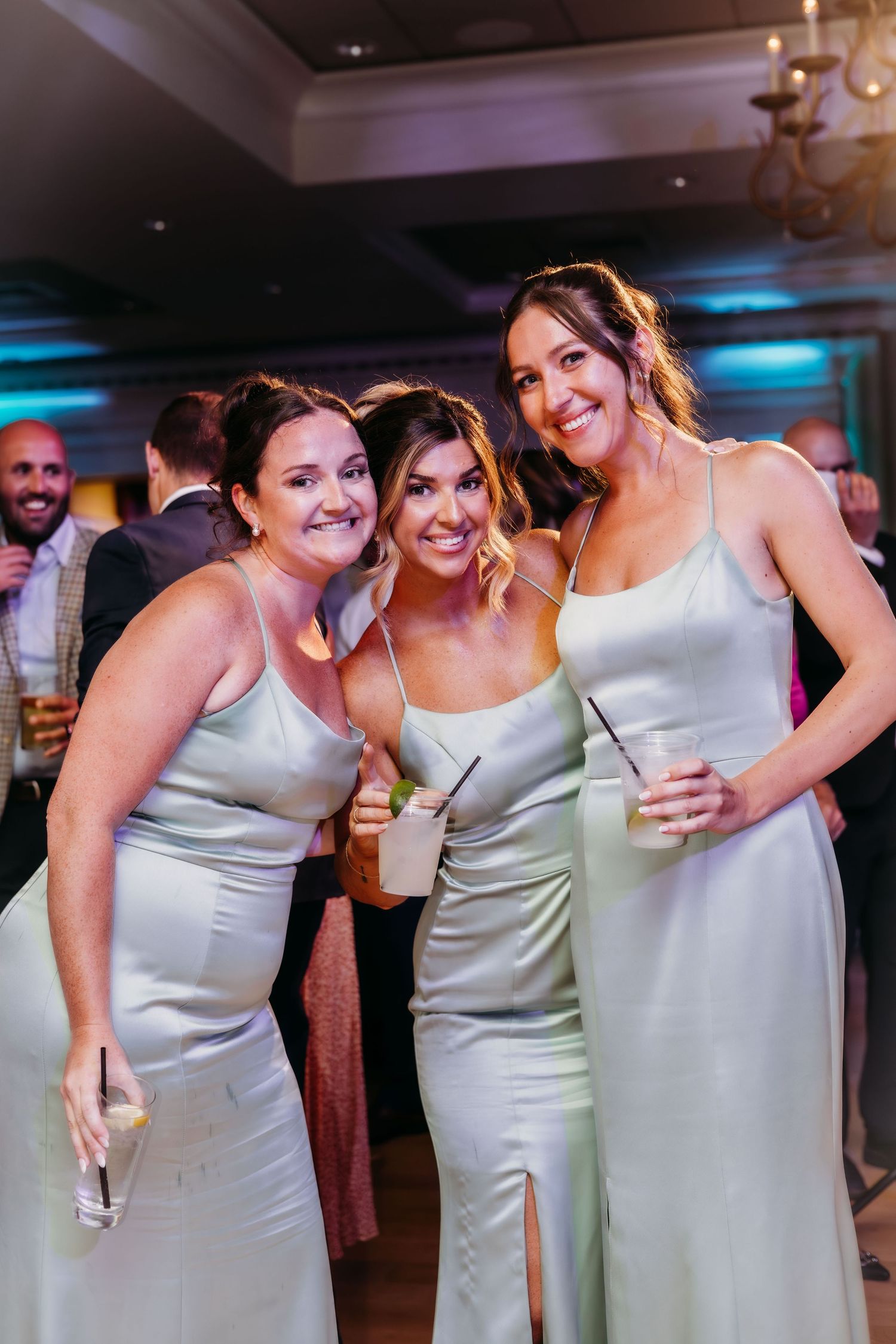 Bridesmaids in silver satin dresses sharing a fun moment at a wedding reception.