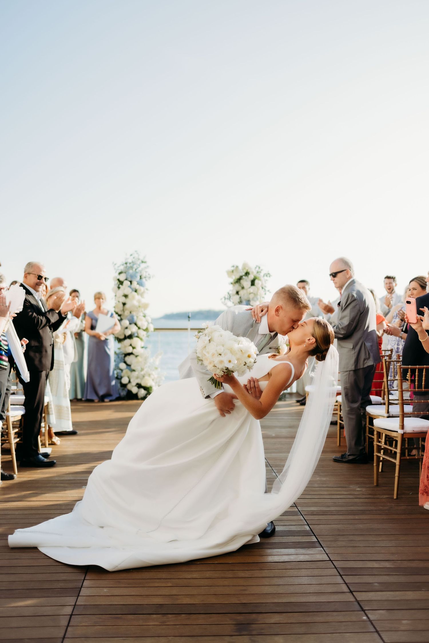 Four sequential photos show a romantic dip during a first dance at an outdoor waterfront wedding reception.