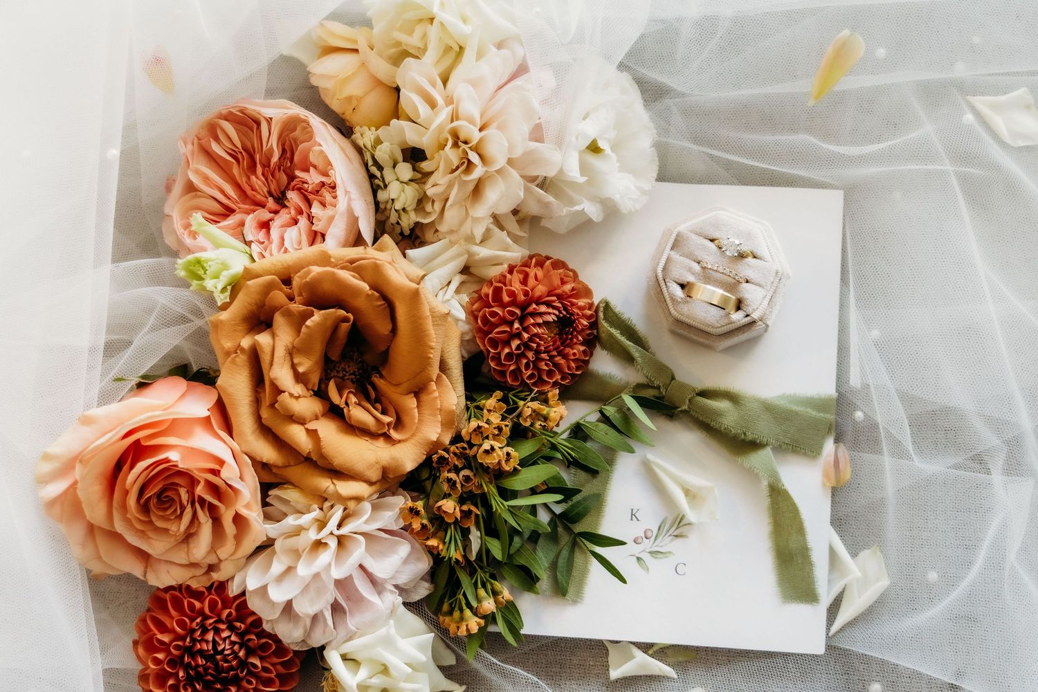Delicate floral arrangements with peach and coral roses alongside white flowers on a light fabric backdrop.