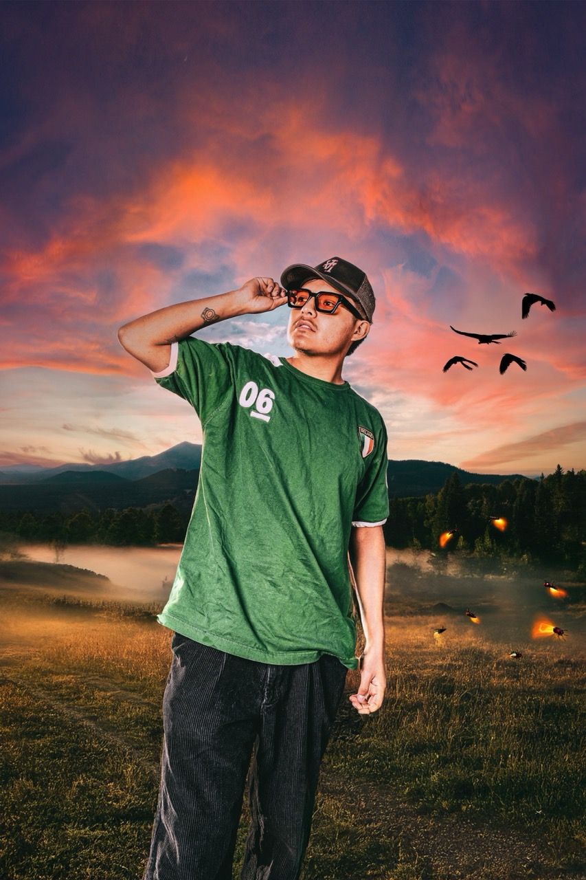 A person in a green t-shirt stands in a field at sunset with floating orbs creating a dreamlike mood.
