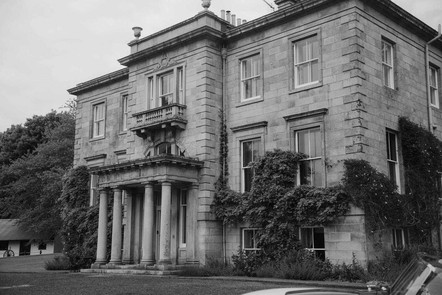 Exterior view of a grand historic stone mansion with classical architectural features.