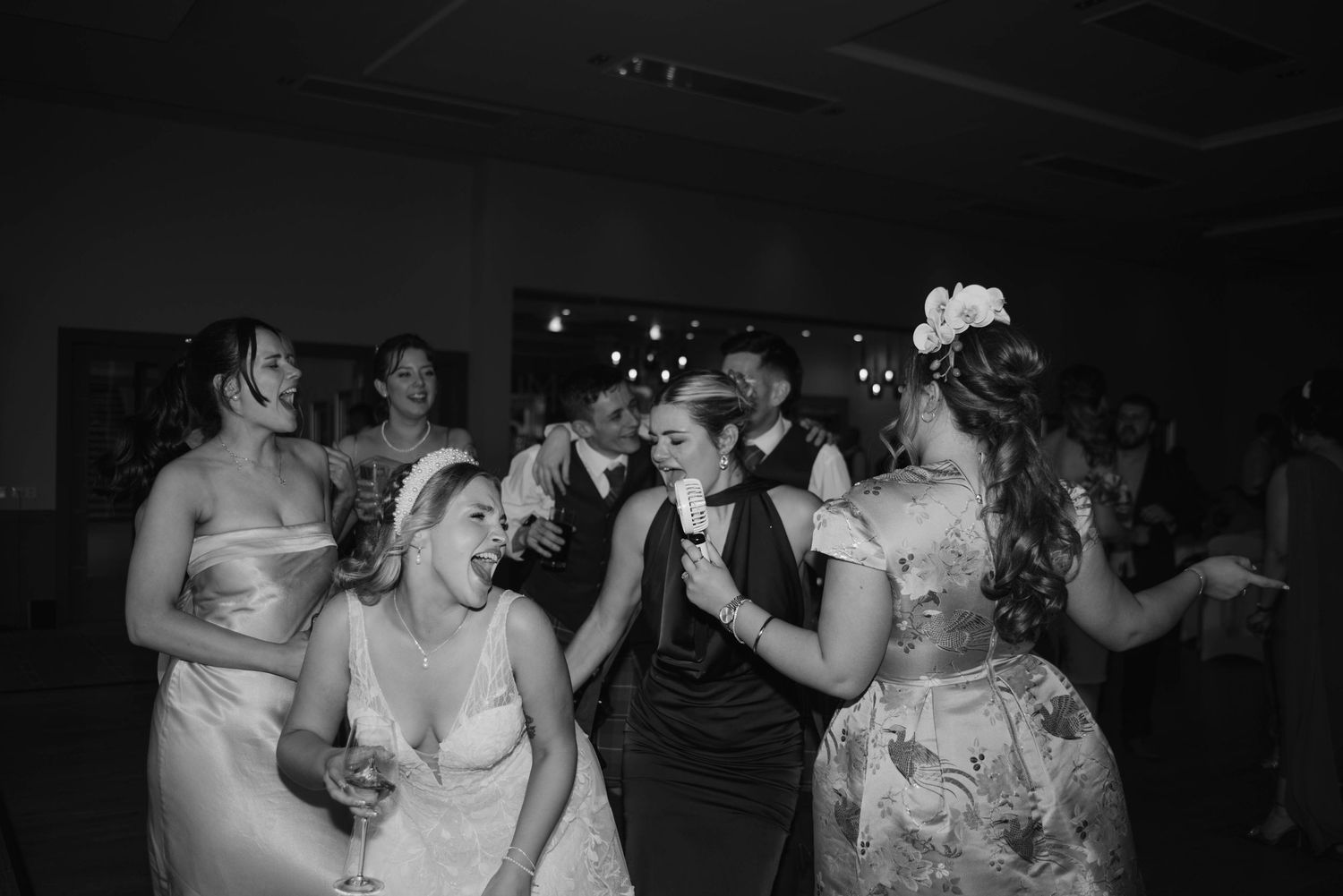 Wedding celebration captured in black and white with guests dancing enthusiastically.