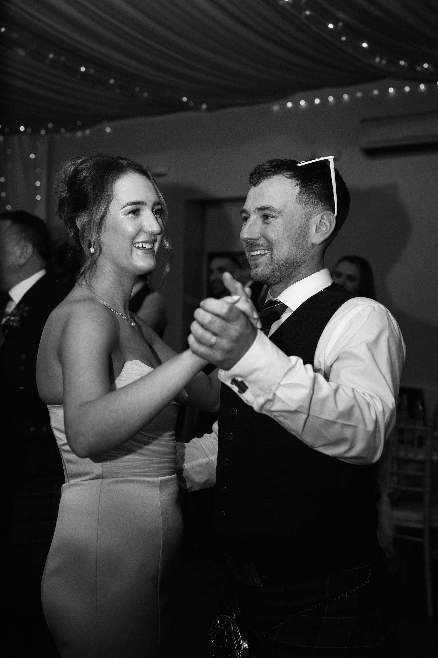 Wedding couple sharing an intimate dance moment under decorative lighting.