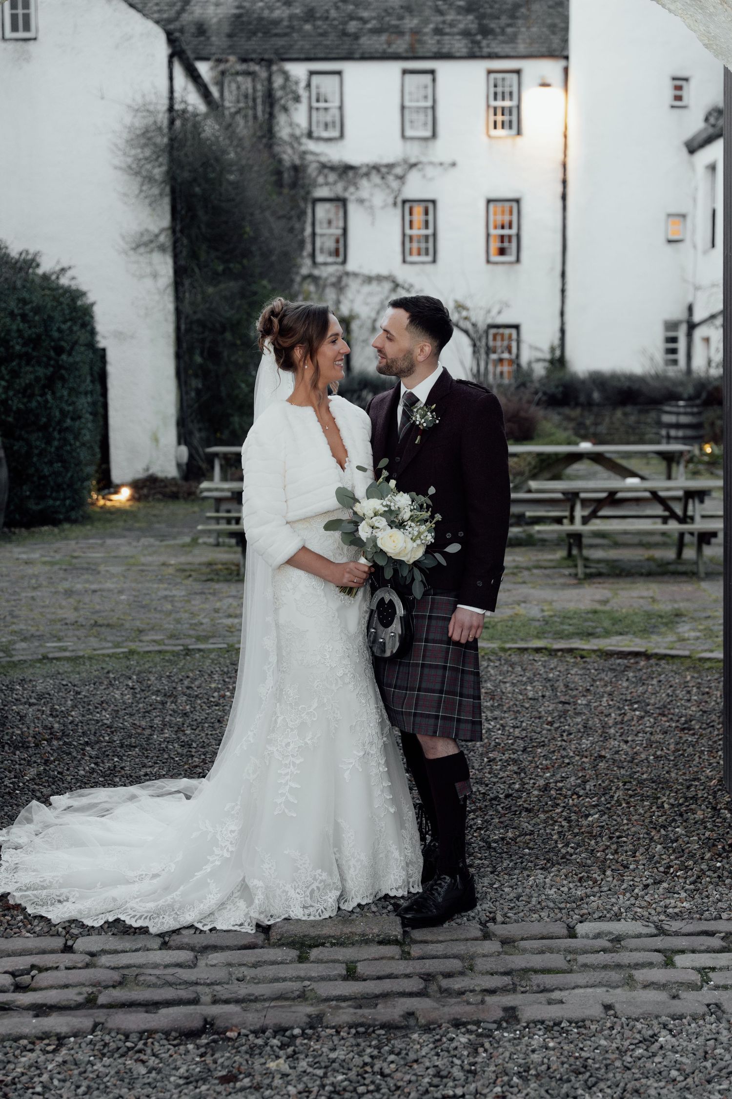 Intimate wedding portrait featuring Scottish traditional dress against historic architecture.