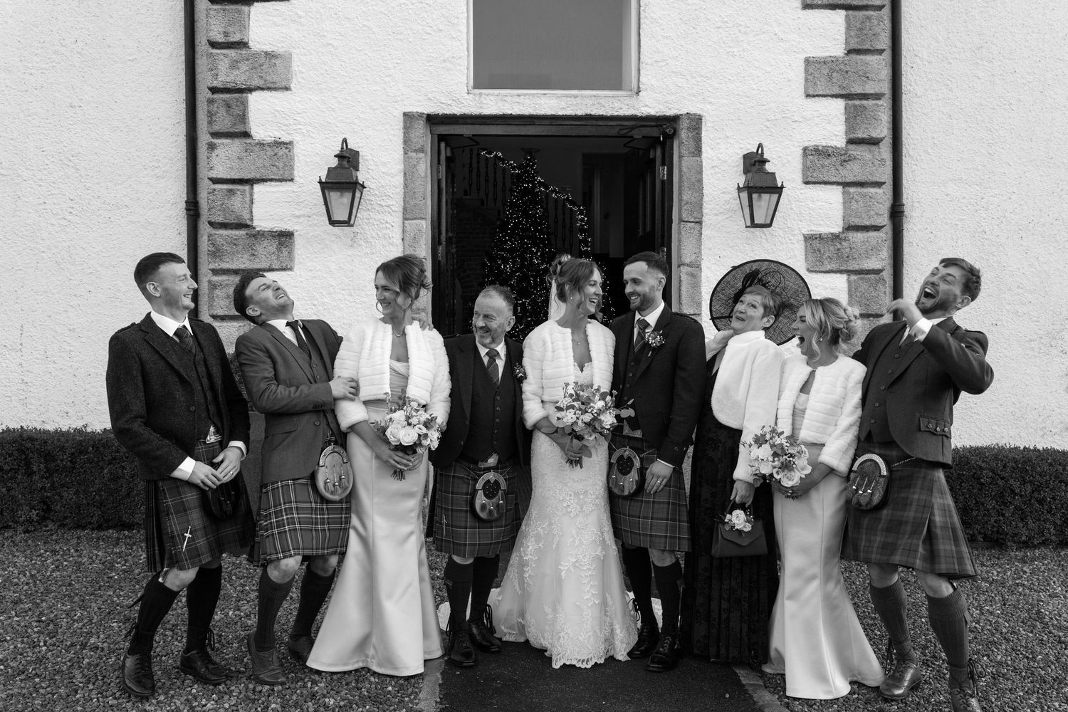 Wedding party lined up against white stone wall with traditional lanterns.