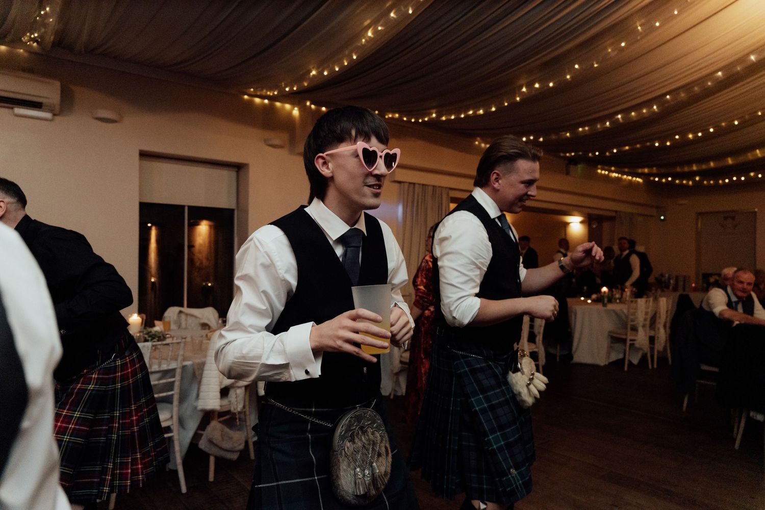 Couples dancing at wedding reception with elegant ceiling draping and ambient lighting.