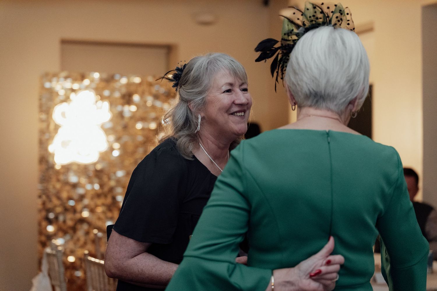 Wedding party members share joyful moments while dancing at an indoor reception venue.