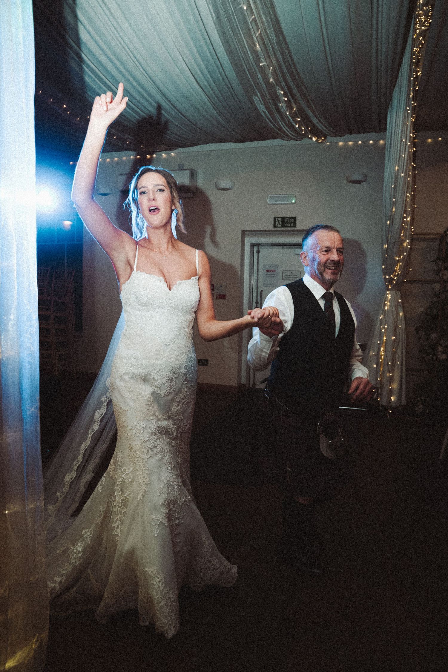 Wedding couple dances together under draped fabric ceiling with twinkle lights.