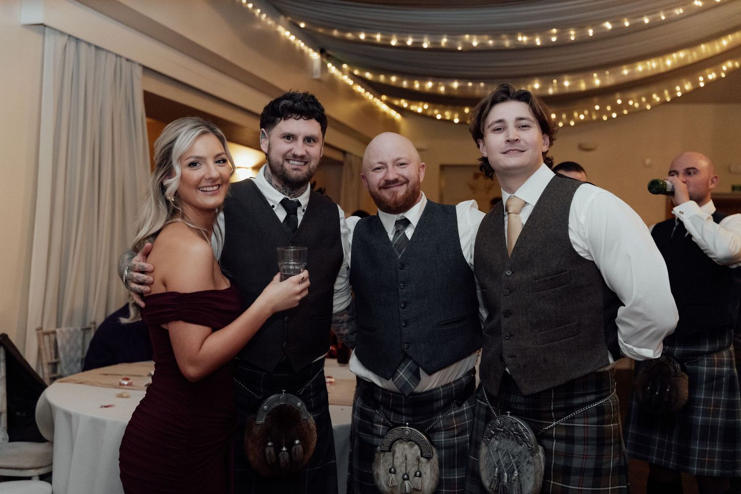Wedding reception venue decorated with twinkling string lights and white curtains.