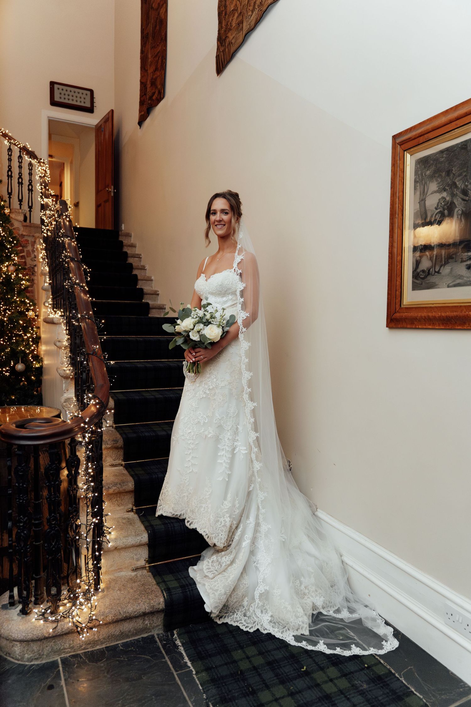 Beautiful lace wedding dress with long train captured in an elegant indoor setting with festive lights.
