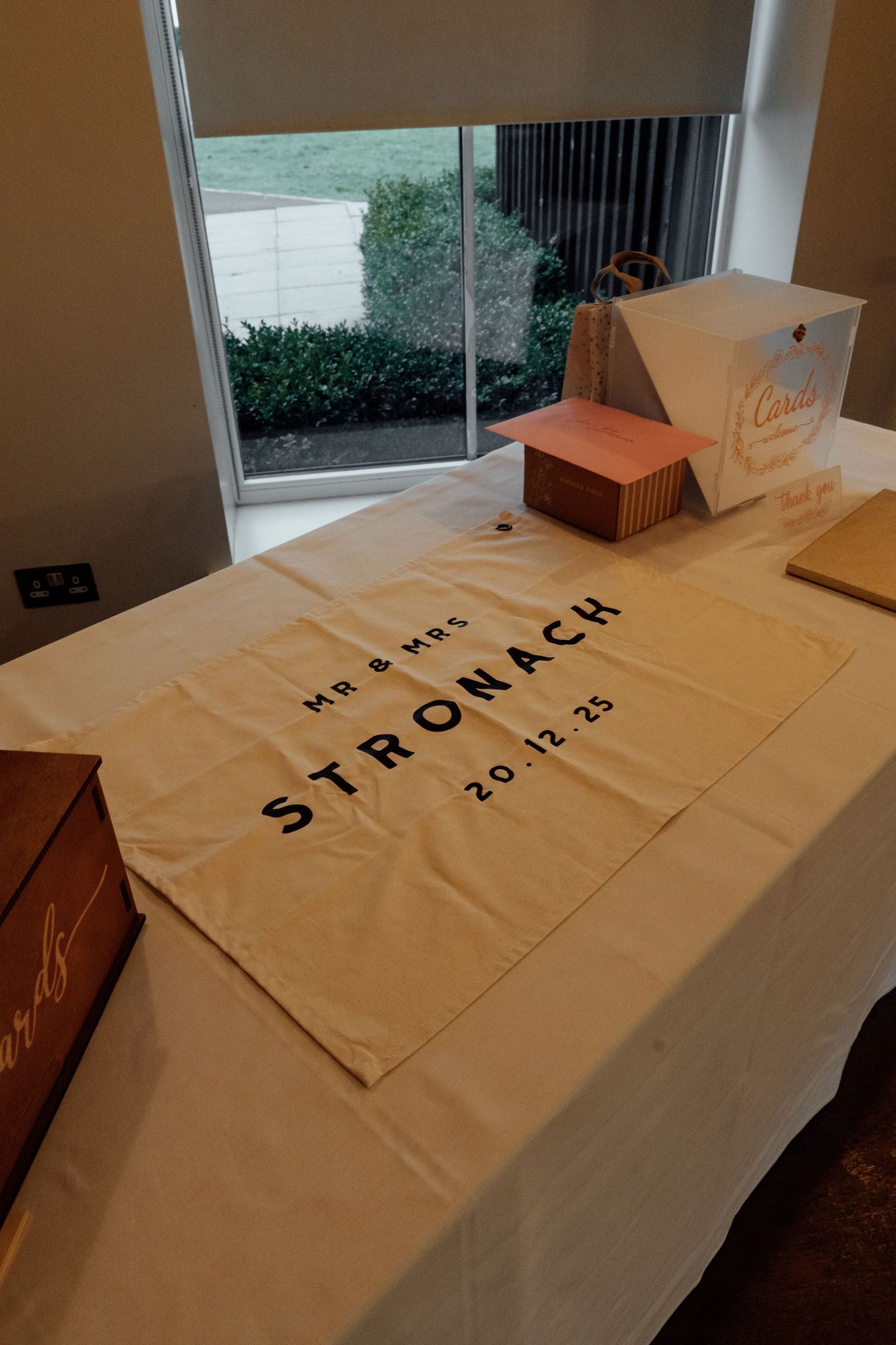 Wedding table with 'Stromack' text displayed on white tablecloth next to boxes.