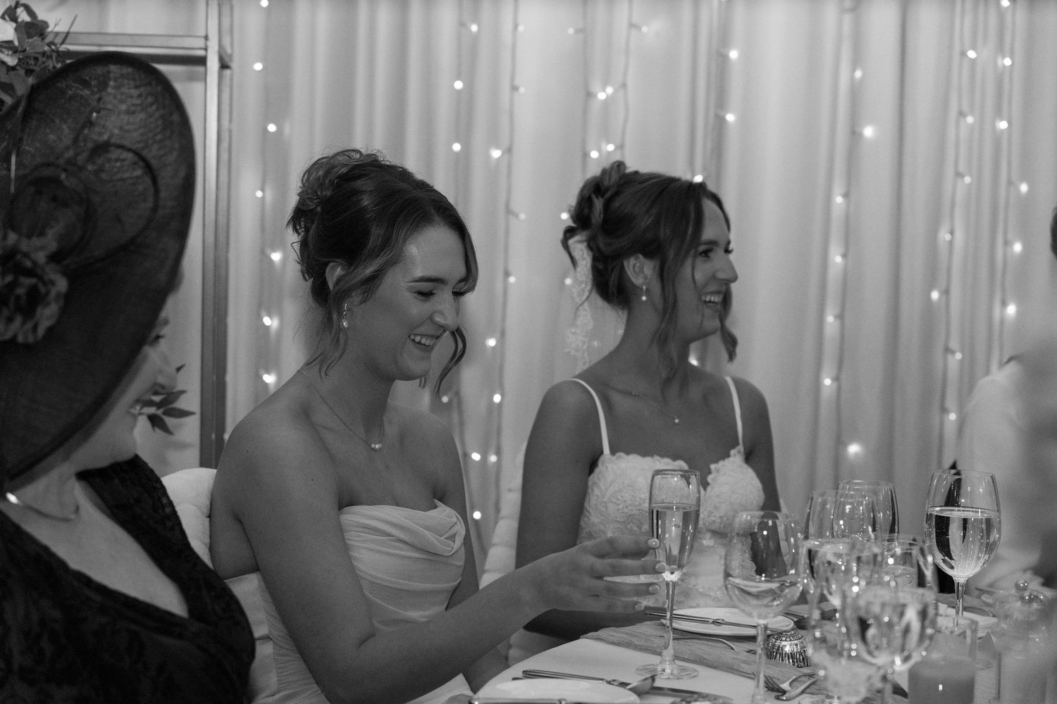 Wedding dinner setup with elegant table settings and twinkling fairy lights in the background.