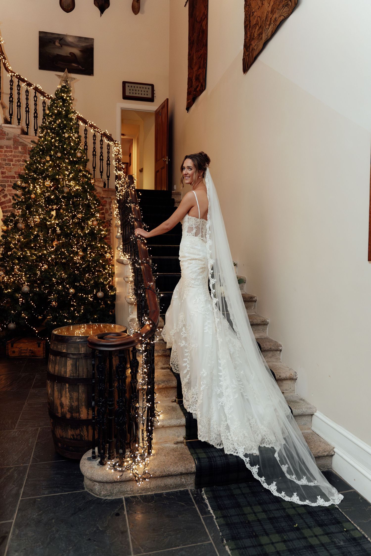 Wedding dress detail shot showing intricate lace train against holiday-decorated indoor setting.