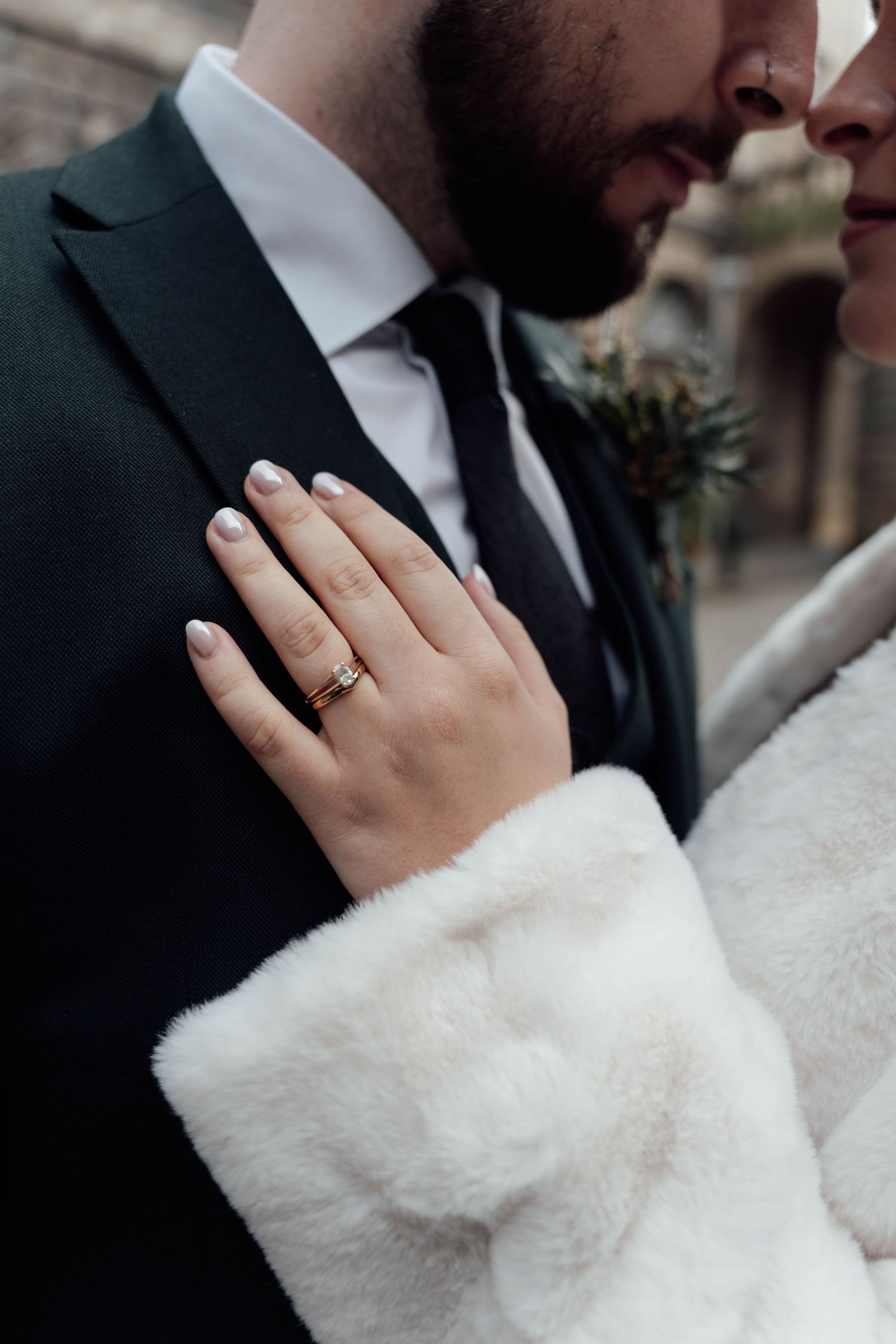 Intimate wedding moment showing hands with rings and white fur details.