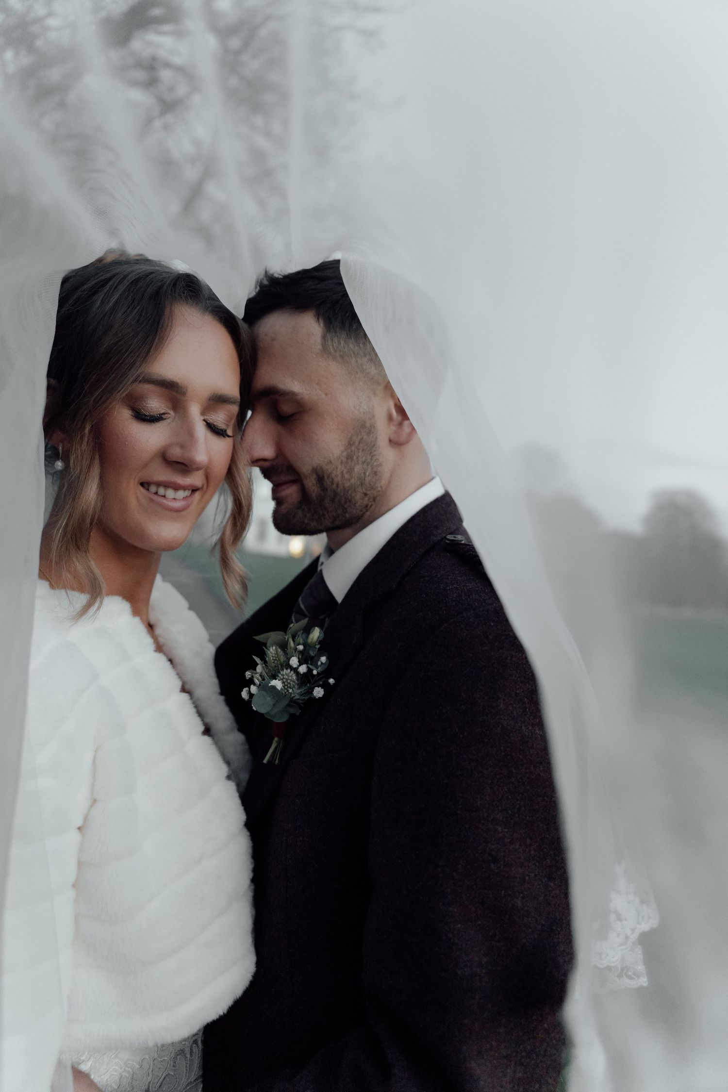 Atmospheric wedding photos capturing tender moments between the couple in muted tones.