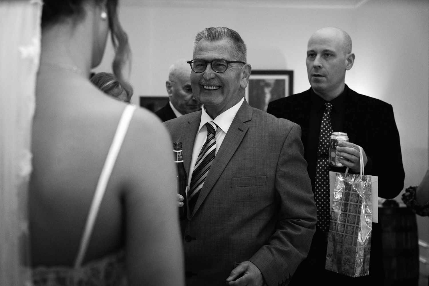 Black and white photo of guests socializing at an elegant indoor reception.