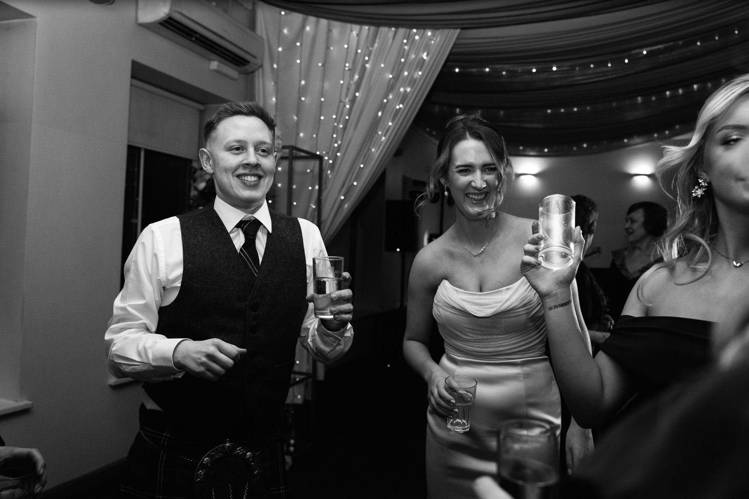 Guests enjoying drinks and conversation at an indoor reception with decorative ceiling draping.