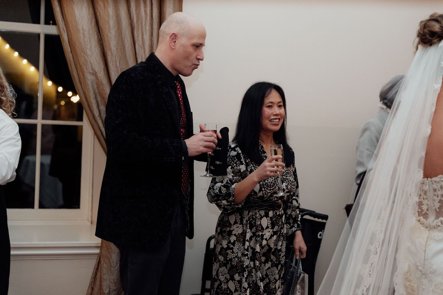 Wedding guests mingle and socialize during an indoor reception event.