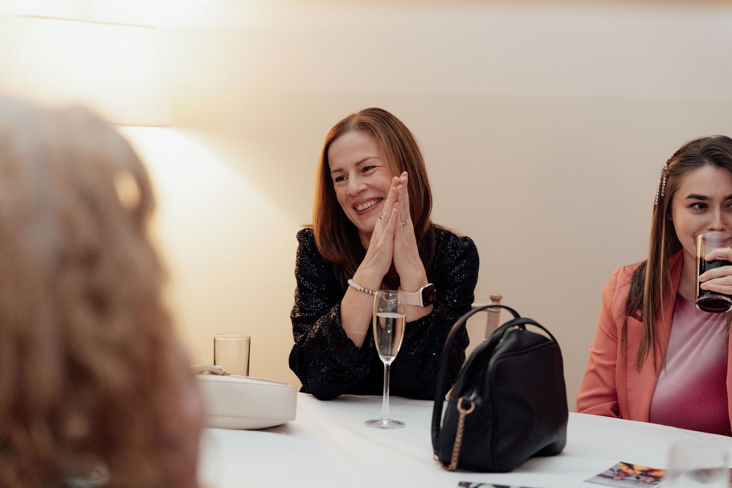 Guests seated at a table share laughter and conversation during a wedding reception.