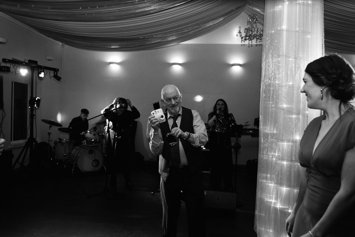 Black and white photo of wedding reception entertainment with illuminated column decor.