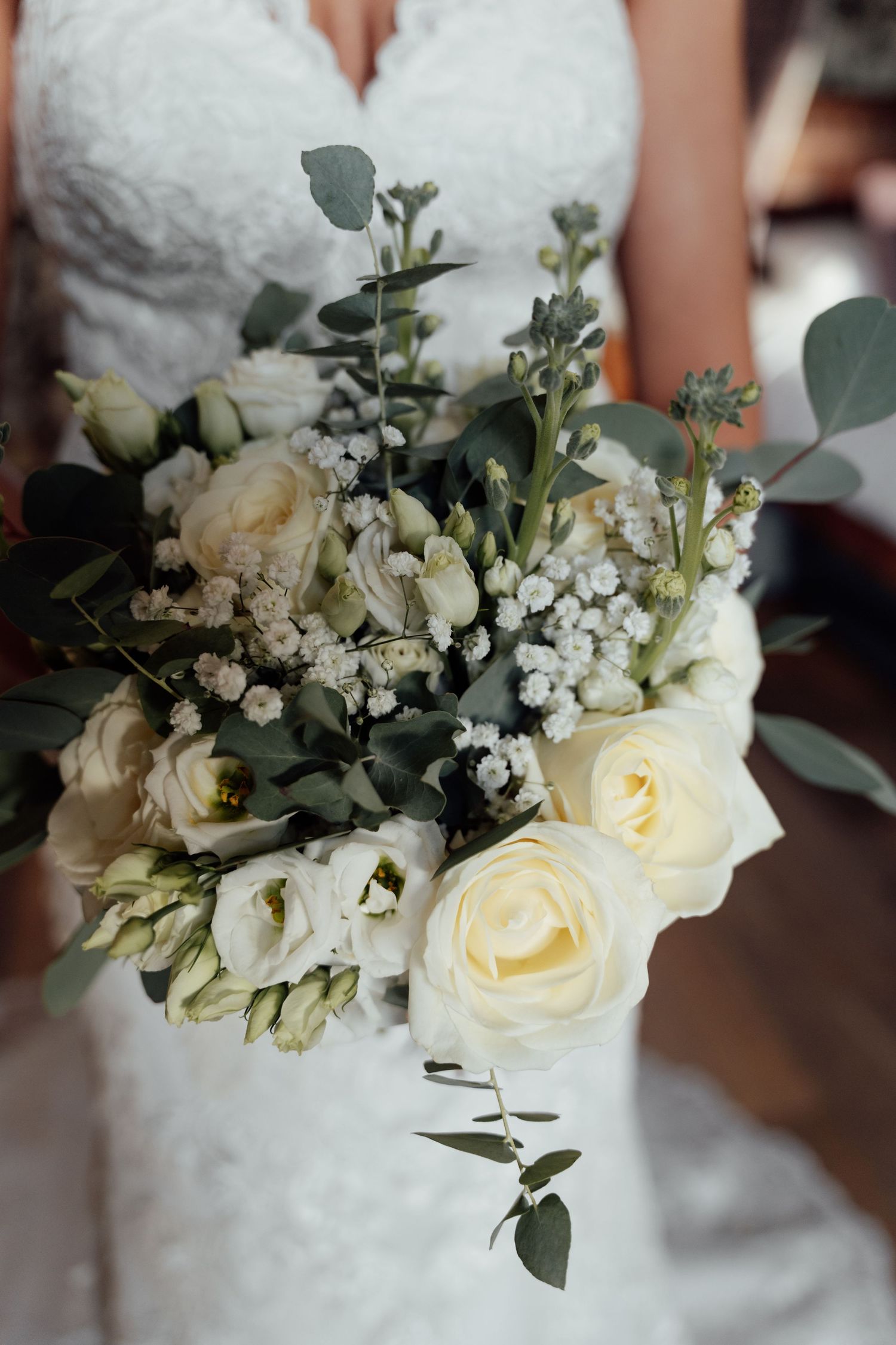 Elegant white rose and baby's breath bridal bouquet with eucalyptus leaves.