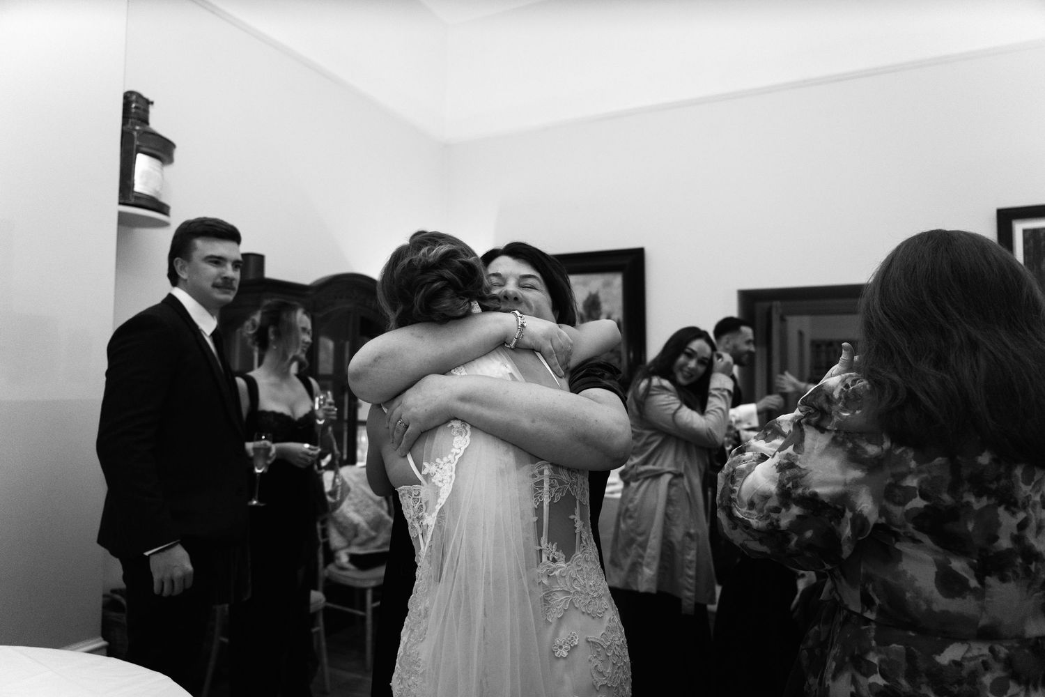 Black and white photo of people embracing during a social gathering.
