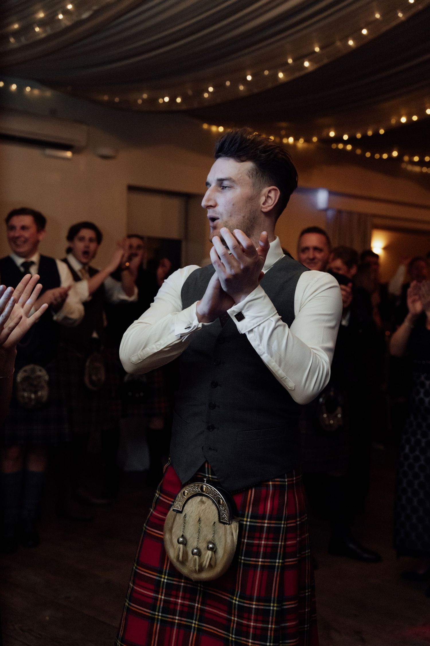 A guest in traditional Scottish kilt reacting emotionally during wedding celebrations.
