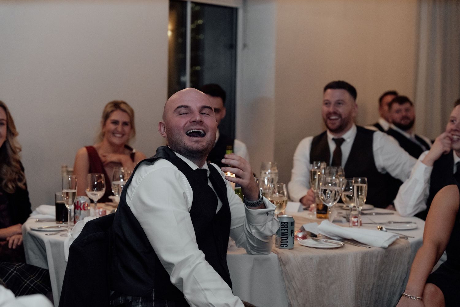 Wedding reception guests socializing at decorated dining tables.