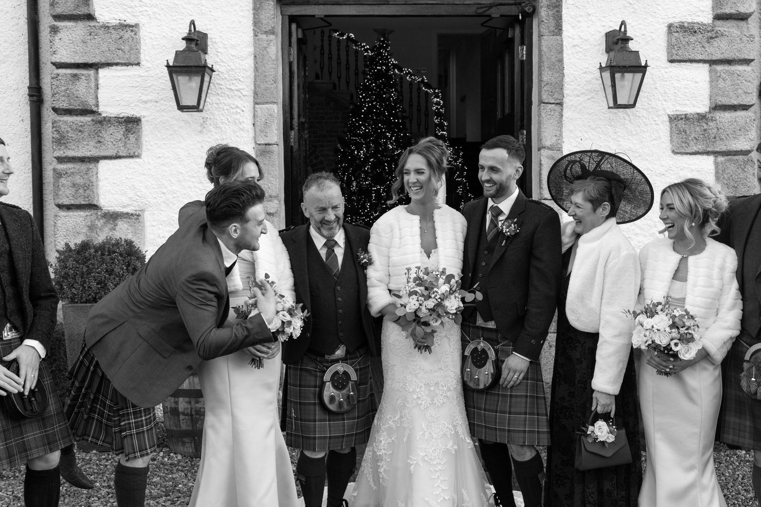 Candid wedding moments captured outside white stone venue with lanterns.