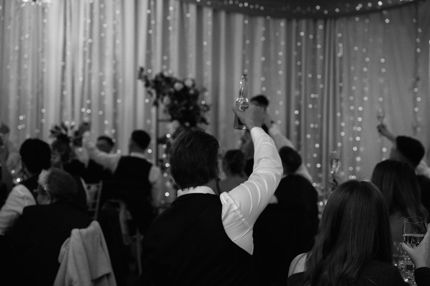 String lights create a romantic ambiance against dark walls at an evening wedding reception.