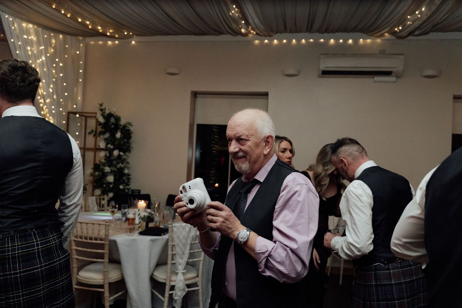 Wedding guest in formal attire enjoys refreshments during reception celebration.