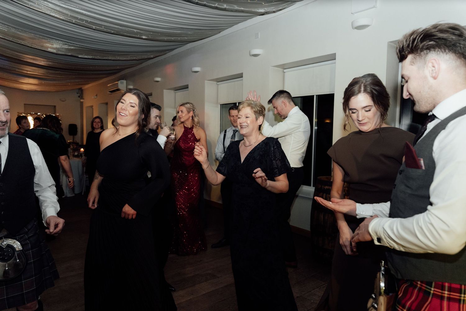 Lively dance floor scene at wedding reception with guests enjoying the celebration.