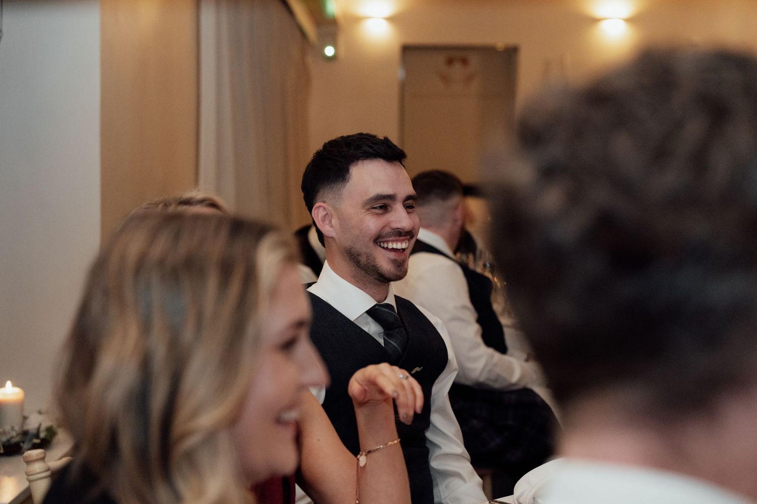 Guests sharing stories and smiles during an indoor wedding celebration.