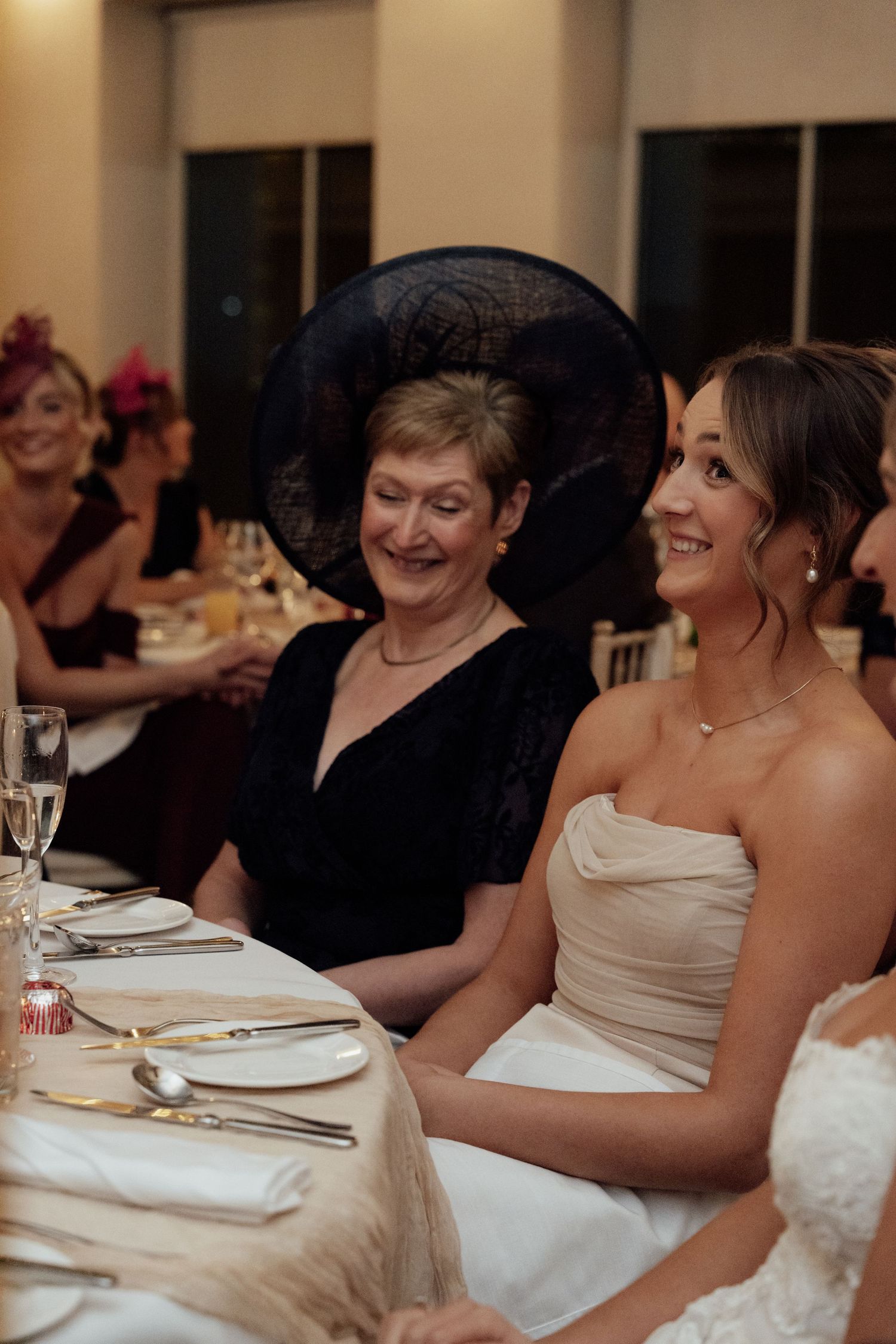 Wedding party guests seated at dinner tables sharing joyful moments.