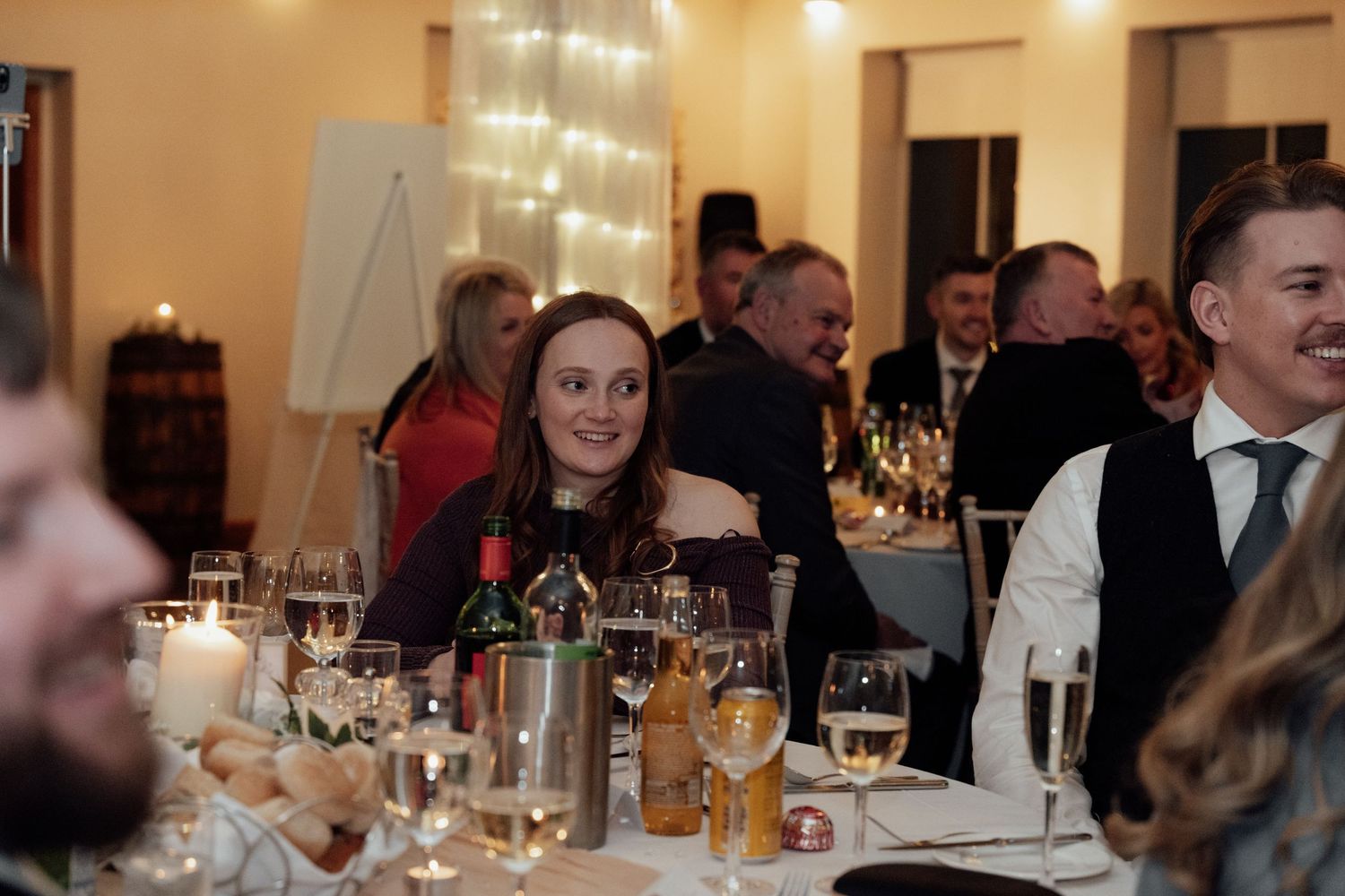 Banquet hall filled with wedding guests dining at tables decorated with glowing centerpieces.