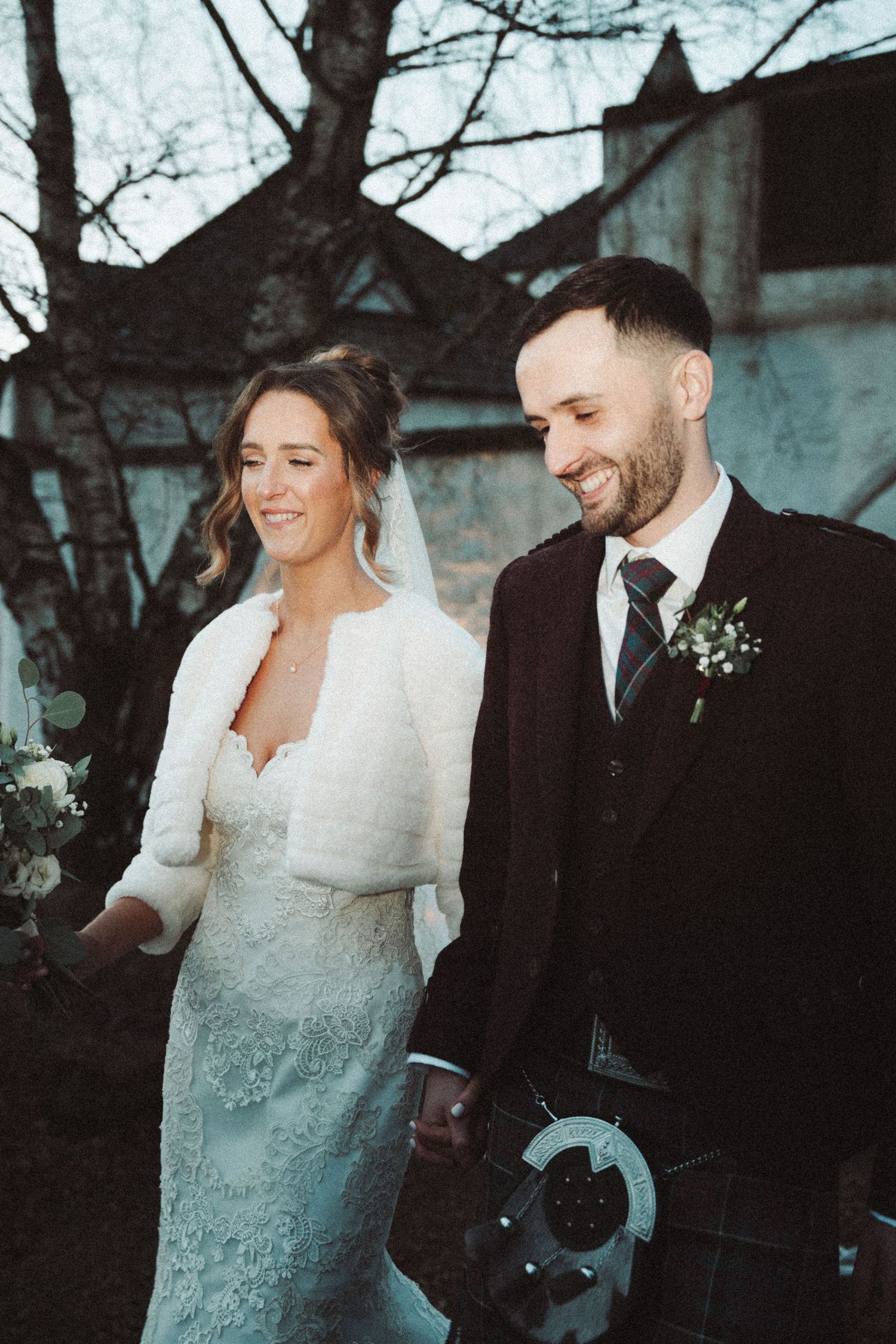 Candid wedding moment captured outdoors with couple in winter wedding attire against historic backdrop.
