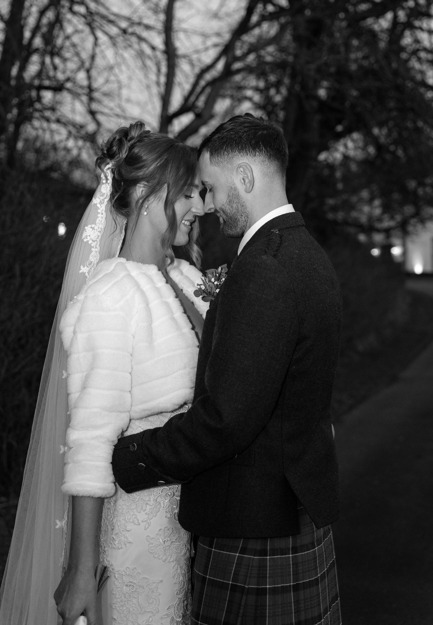 A romantic black and white wedding photo series showing a couple embracing outdoors at dusk.
