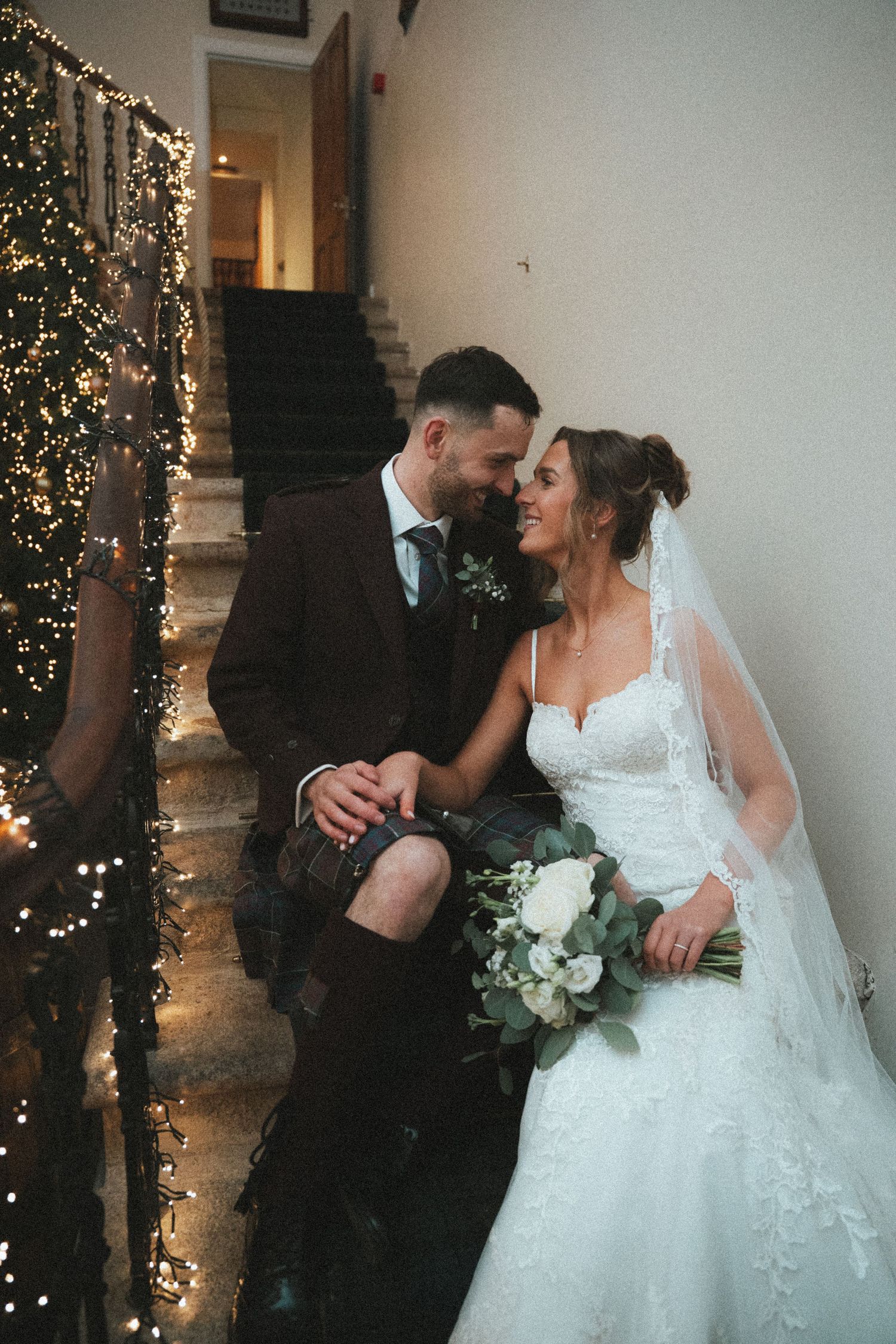 Candid wedding photo with Christmas lights creating warm glow on staircase.