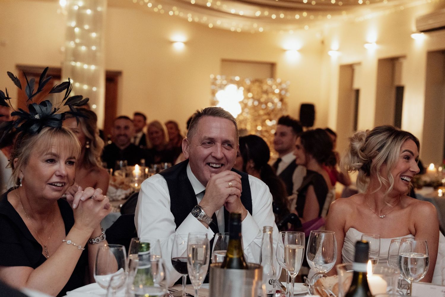Wedding reception venue decorated with string lights as guests enjoy dinner and festivities.