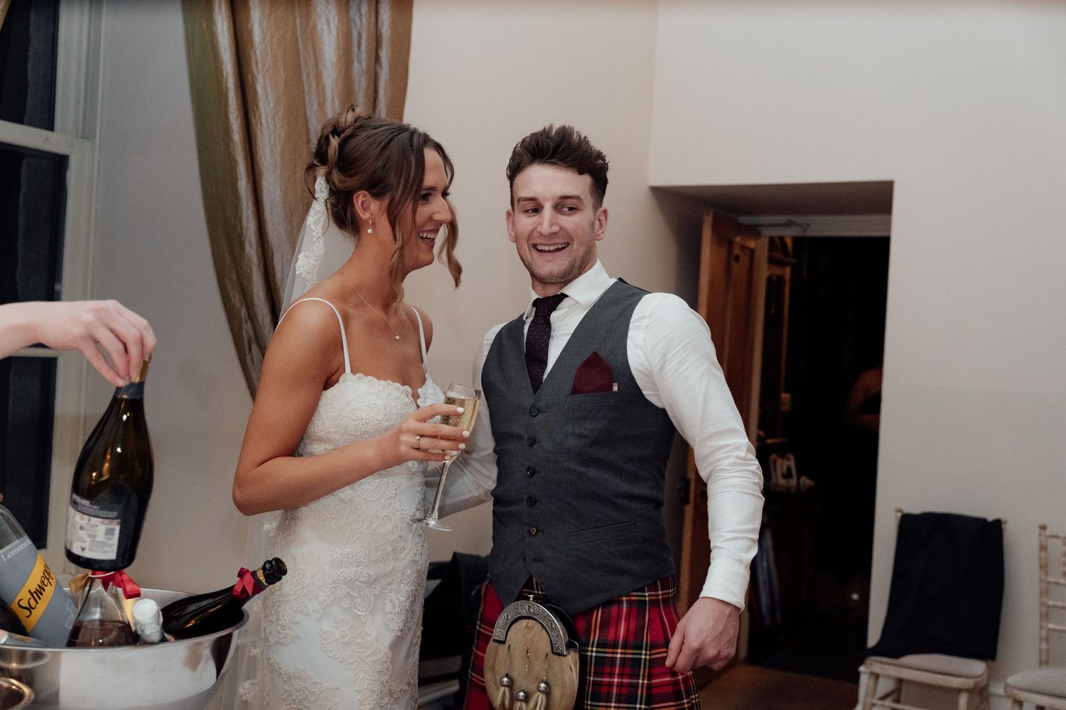 Wedding party members share drinks and laughs at an indoor reception.