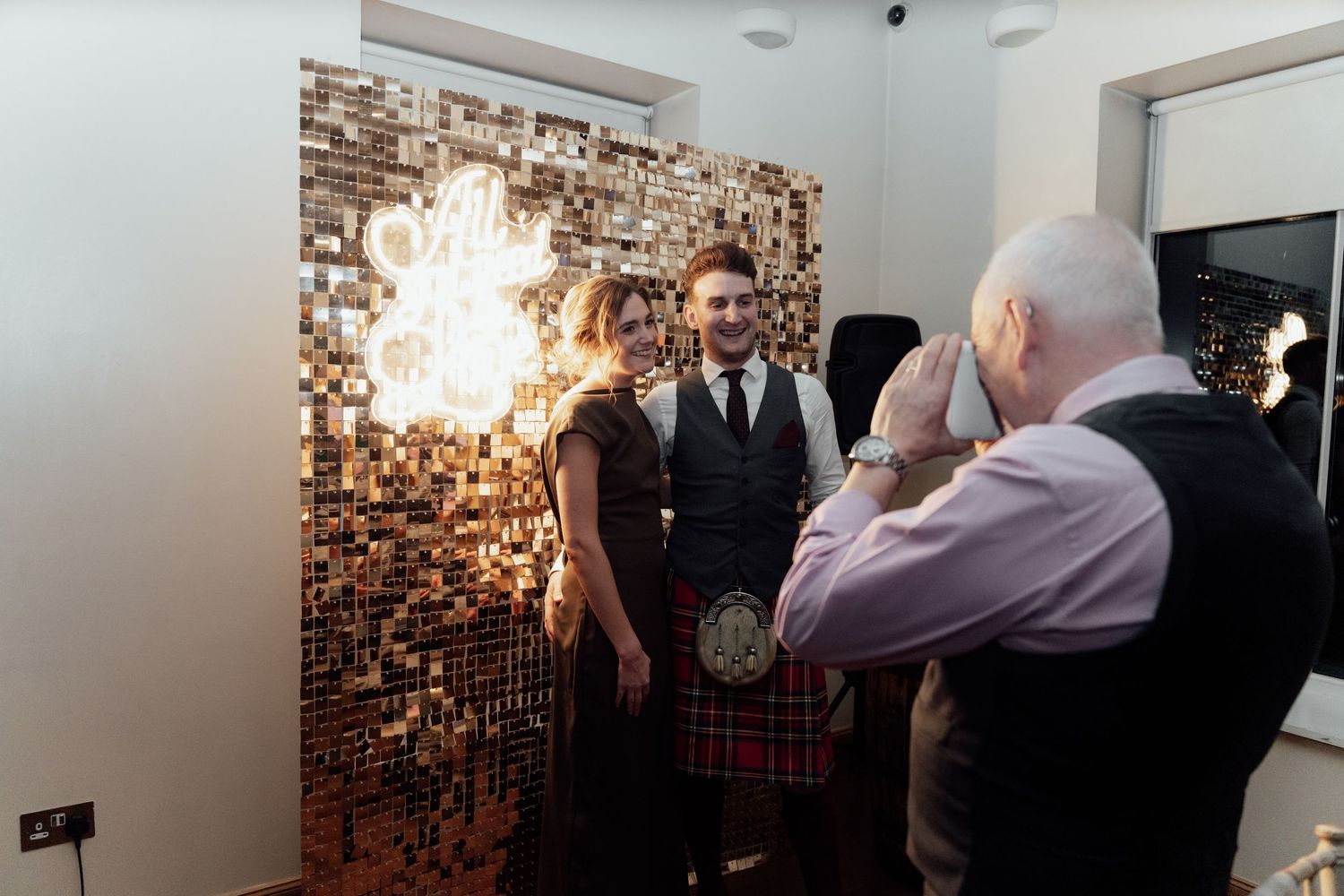 Partygoers gather in a modern room with elegant lighting and textured wall features.