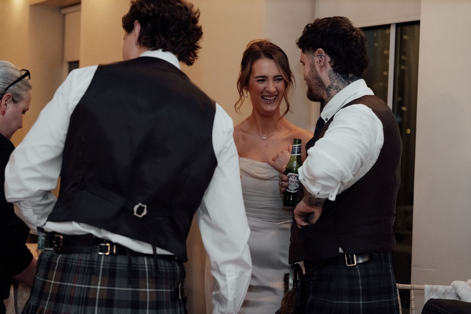 Wedding guests in formal attire and traditional Scottish kilts socialize at an elegant reception.