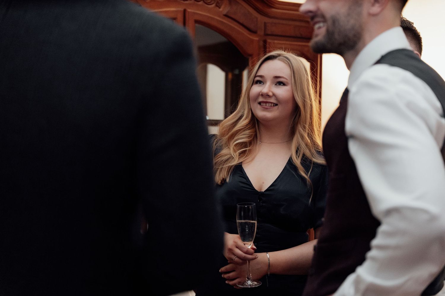 Wedding reception guests interact and socialize while enjoying drinks at a table.