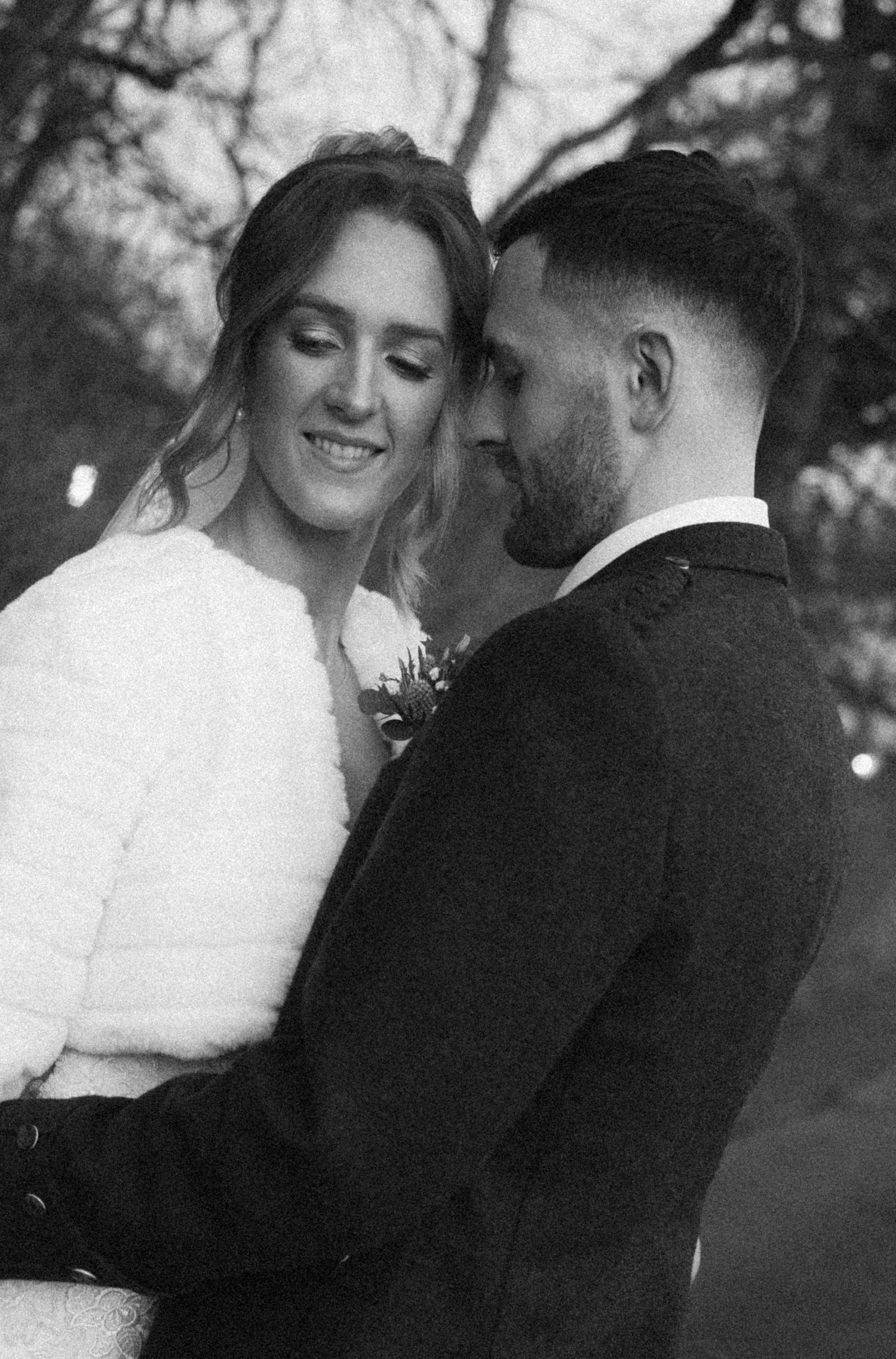 Black and white wedding portraits capturing tender moments between the couple in an outdoor setting.
