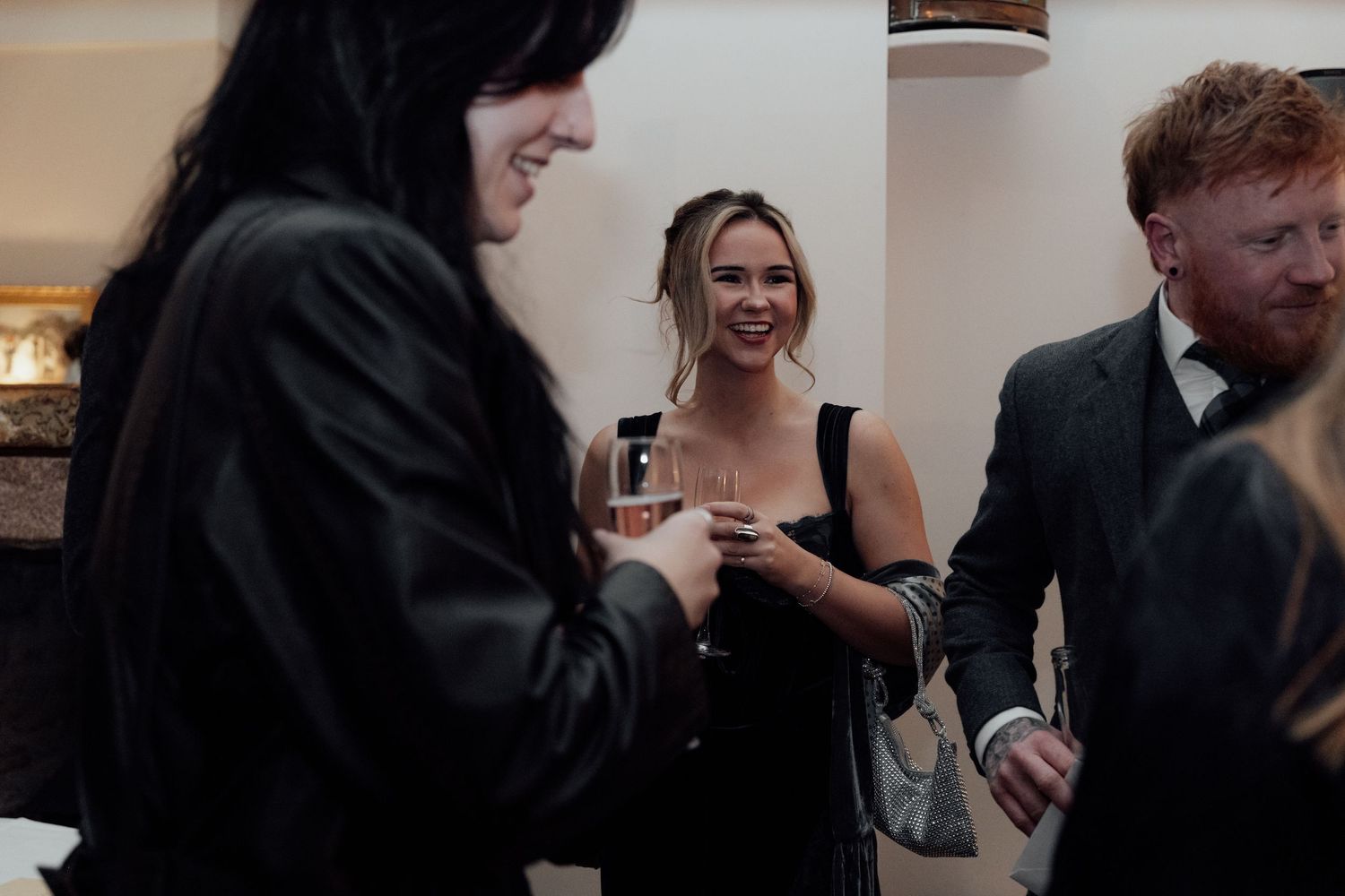 Wedding reception guests engaged in lively conversation at an indoor venue.