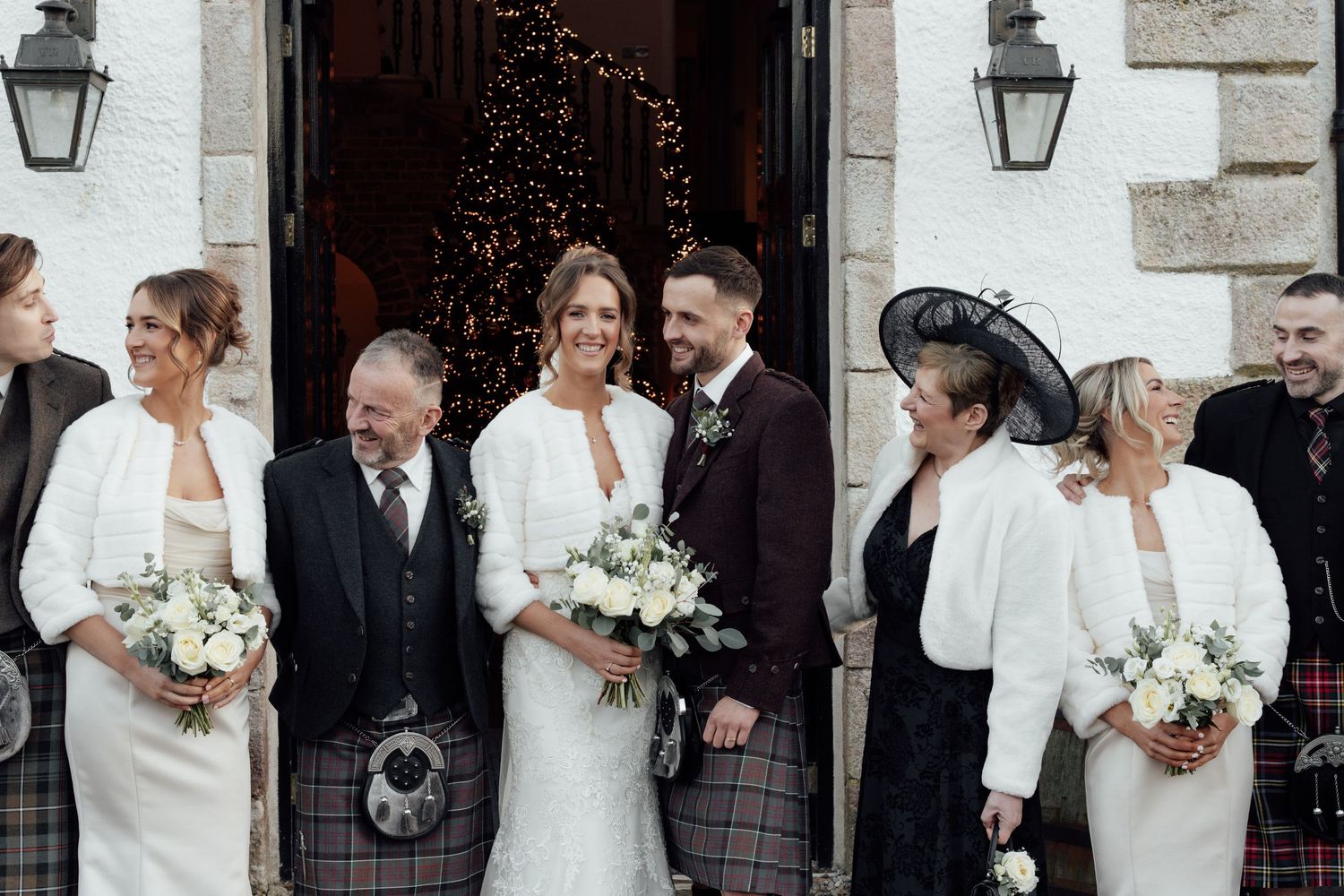 Candid wedding moments captured outside white stone building with traditional Scottish elements.