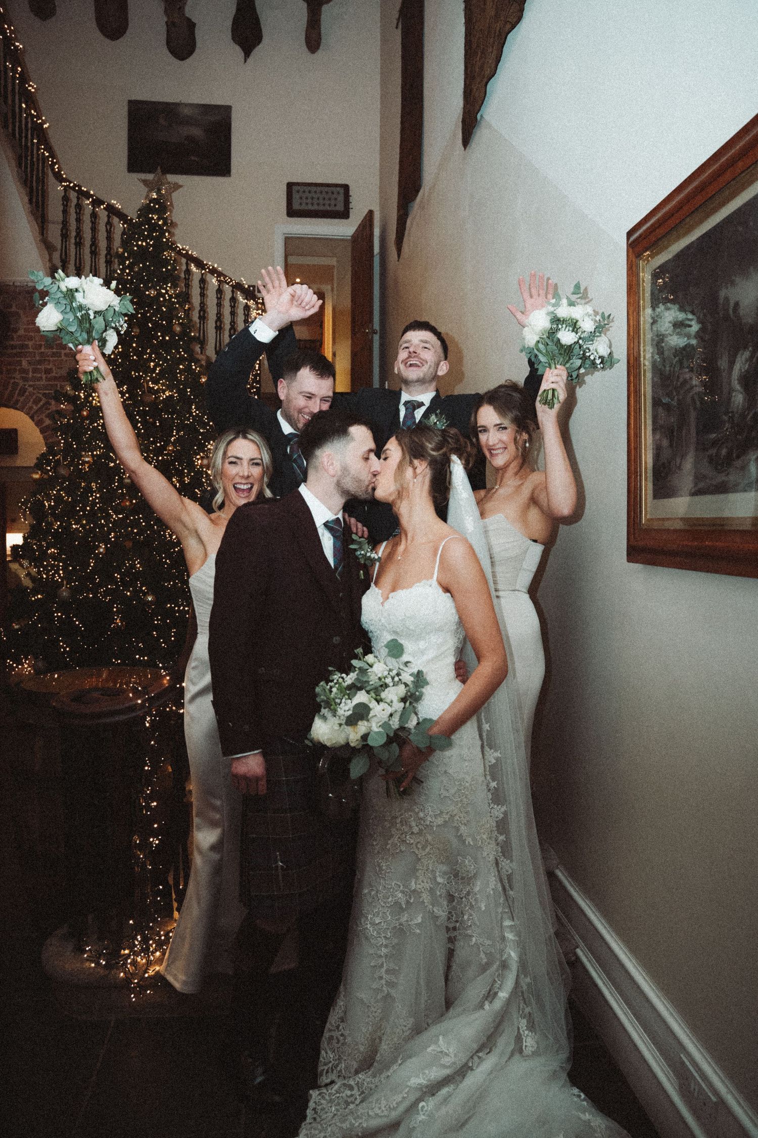Celebratory moment at winter wedding with Christmas tree and white floral bouquets.