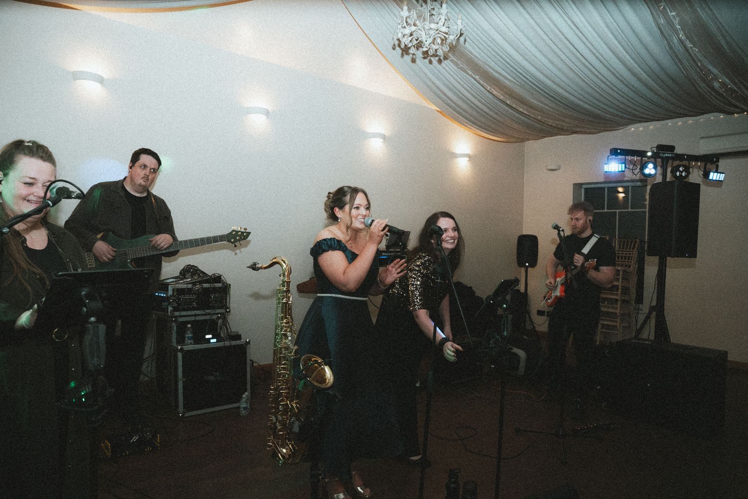 A couple performs their first dance at a wedding reception under draped fabric ceiling with string lights.